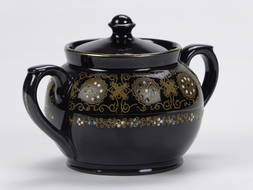 donkerbruin tegen zwart aan aardewerken suikerpot, waarschijnlijk gemaakt in Japan, geometrische goudkleurige motieven , handbeschilderd met emaillen florale motieven, gemerkt aan onderkant met 3 blauwe emaillen stippen, ronde deksel met ronde knop, 2 ronde oren met kleine voluut bovenkant, afkomstig van zeevarende veenkoloniale familie